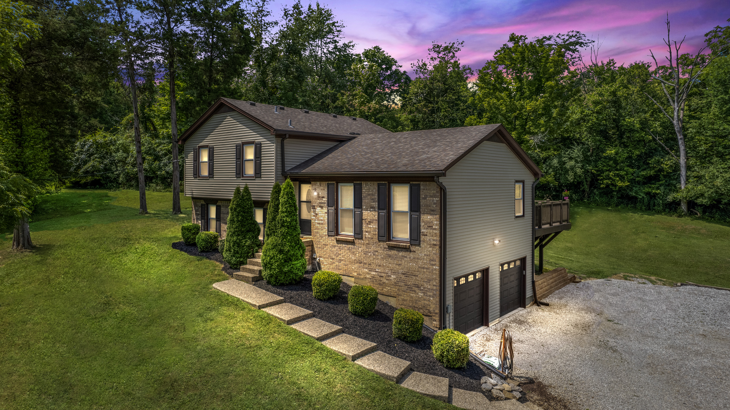 A digitally transformed twilight scene of the same modern suburban home, where soft, warm lights illuminate the exterior and a rich, dusky sky enhances the overall ambiance.